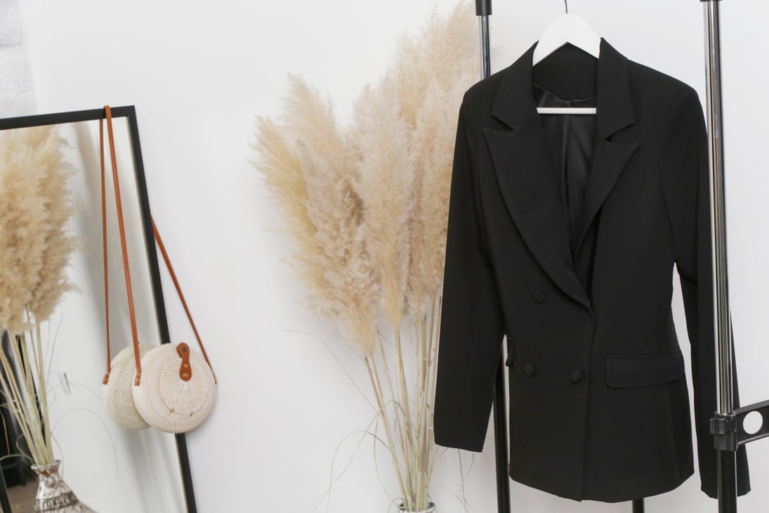 Women's Clothes. Clothes rack, black blazer in fashion atelier.